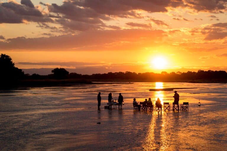 A group of people standing in a shallow lake during sunset